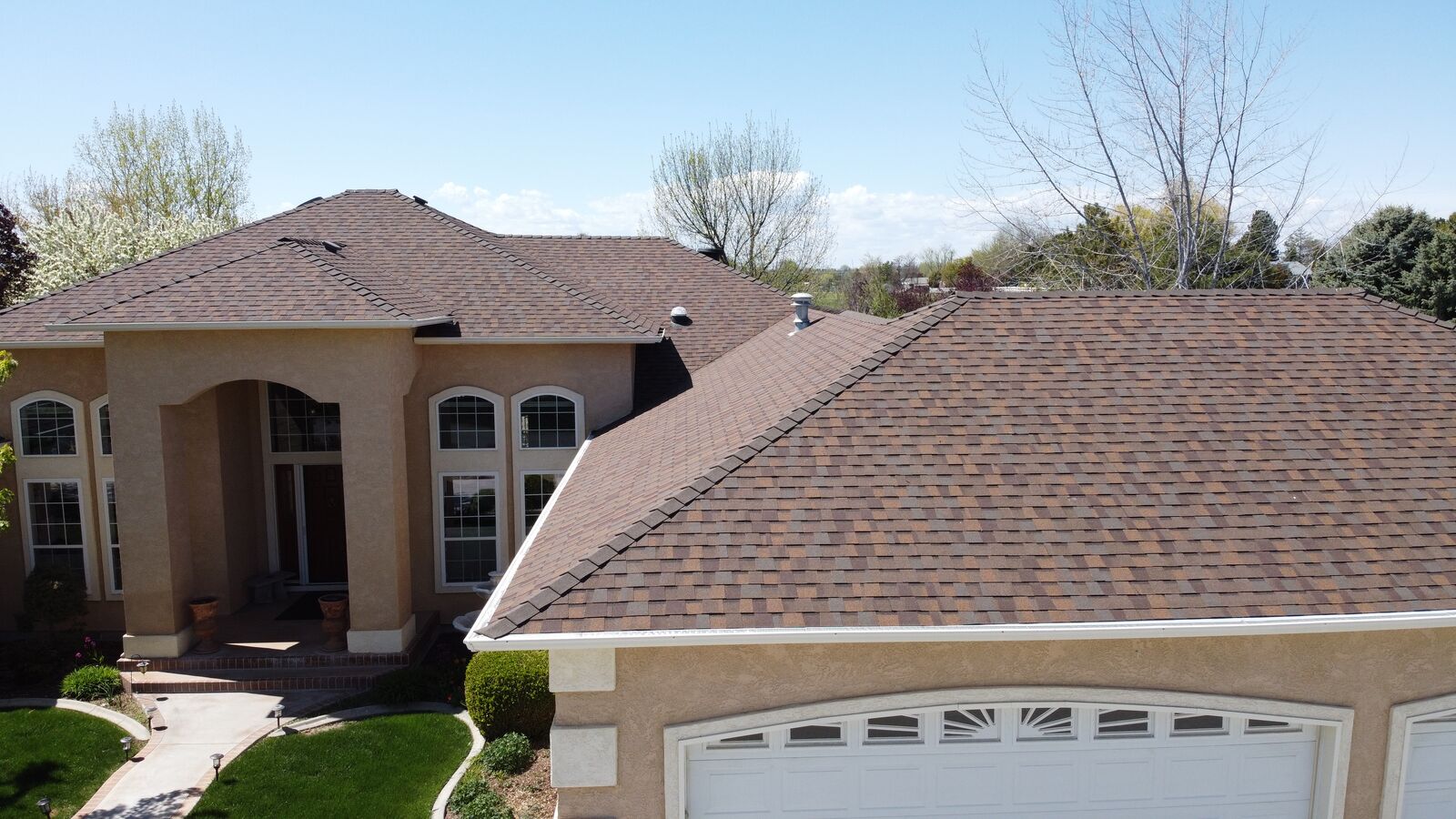 Stucco Mediterranean home with new brown shingle roof in Eagle Idaho