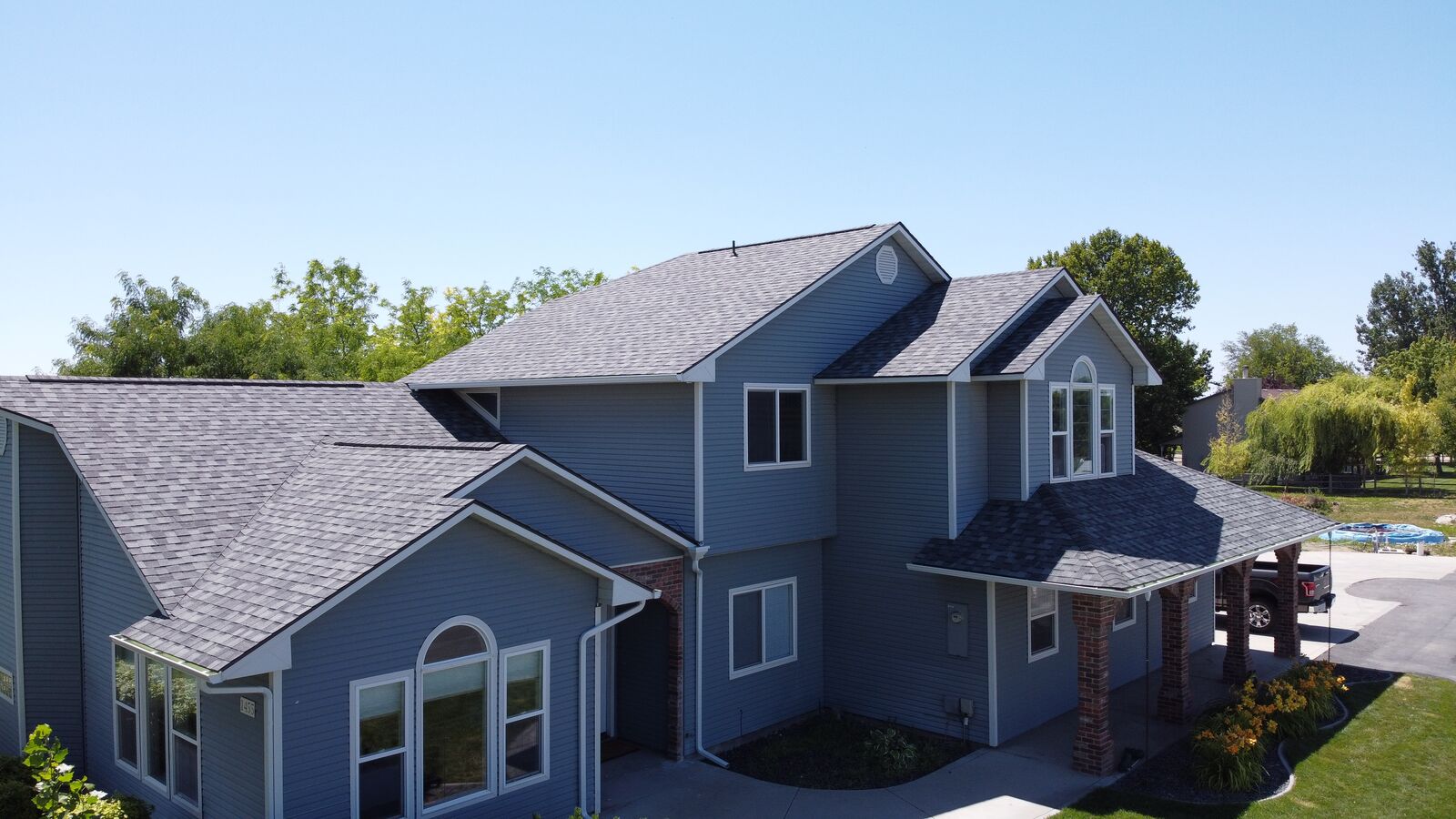 Aerial drone view of completed roof replacement on blue-grey siding home in Kuna Idaho
